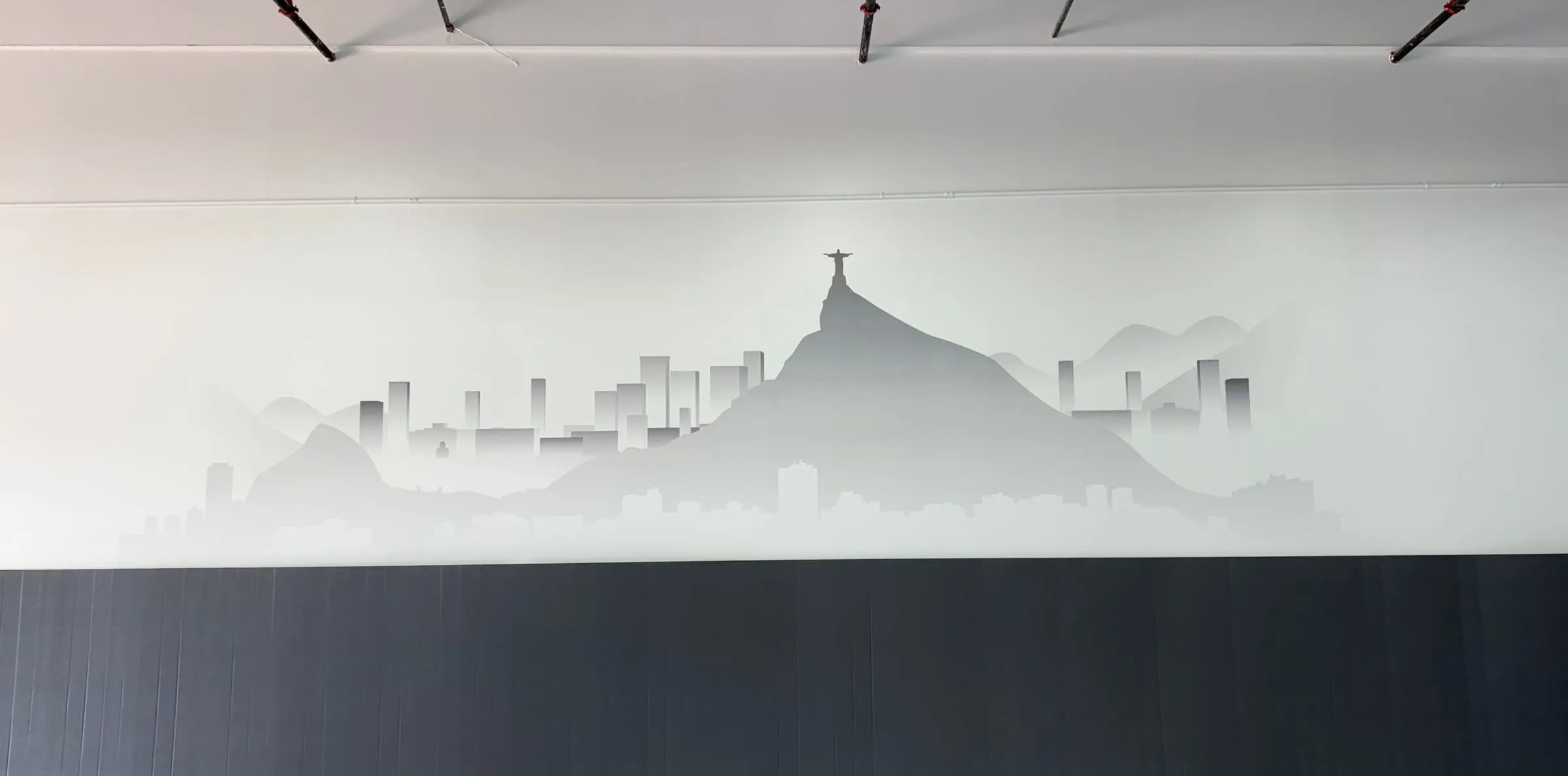 Soft grey Rio de Janeiro skyline with Christ the Redeemer printed across a long gym wall above padded wall mats